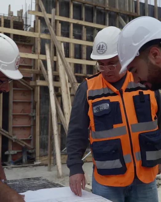 Engineers in hard hats and safety vests reviewing plans on a construction site