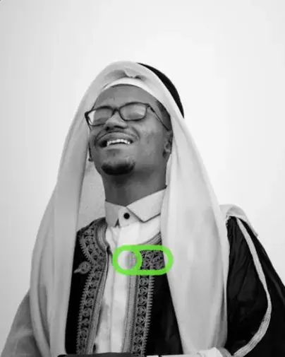 A smiling man in glasses and a white head scarf, in black and white